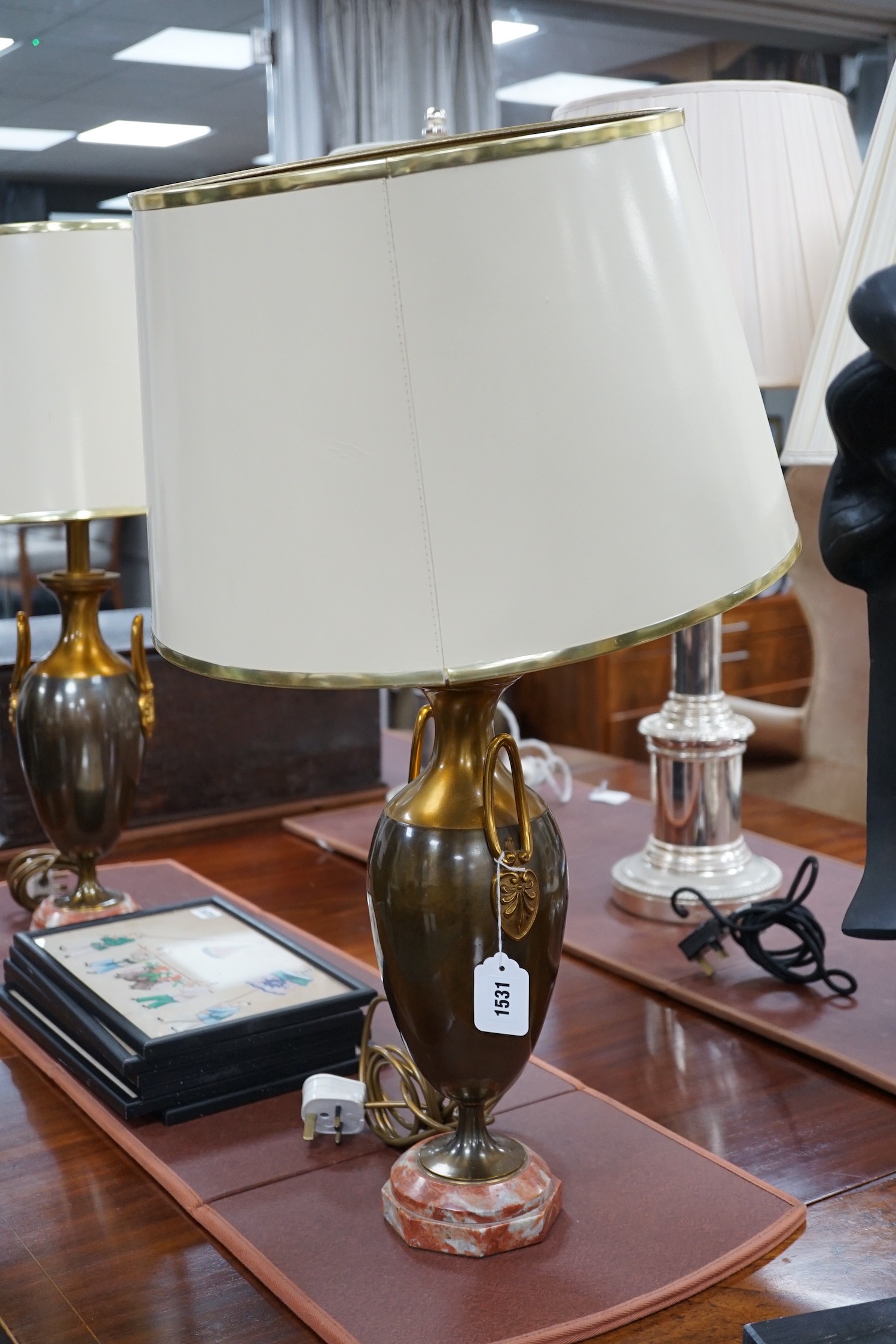 A pair of metal two handled table lamps on marble bases with cream shades, 75cms high